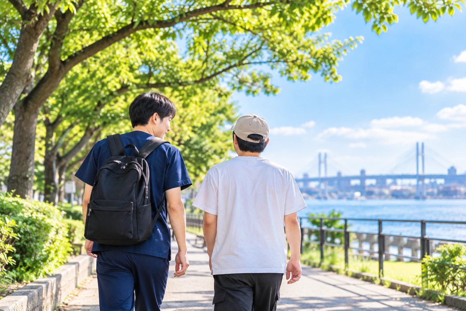 スタッフと利用者が海沿いの遊歩道を並んで歩いている後ろ姿